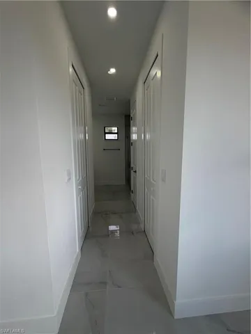 Hallway featuring light marble finish floors and recessed lighting