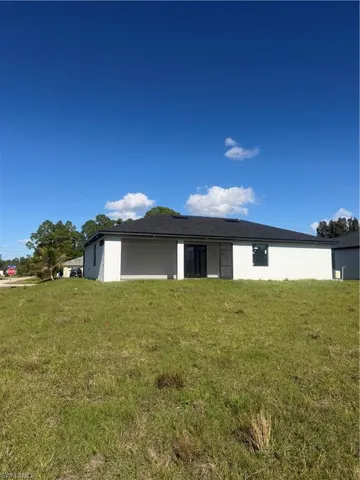 Back of house featuring a yard and stucco siding