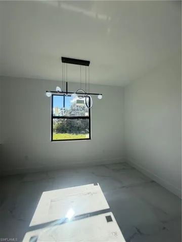 Unfurnished dining area with baseboards and marble look tiles