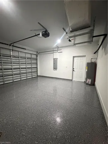 Garage featuring water heater, a garage door opener, and electric panel