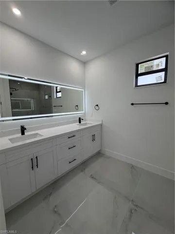 Full bathroom featuring double vanity, light marble finish floors, a shower stall, and recessed lighting