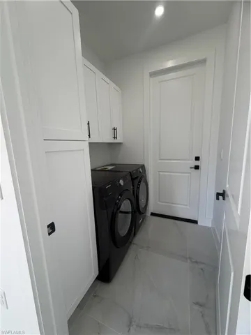 Laundry room featuring light marble finish floors, cabinet space, separate washer and dryer, and recessed lighting