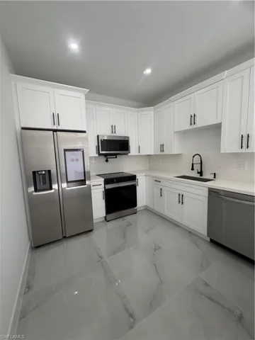Kitchen featuring fridge, white cabinetry, stainless steel stove, dishwasher, and recessed lighting