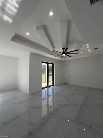 Spare room with light marble finish flooring, a raised ceiling, recessed lighting, and ceiling fan