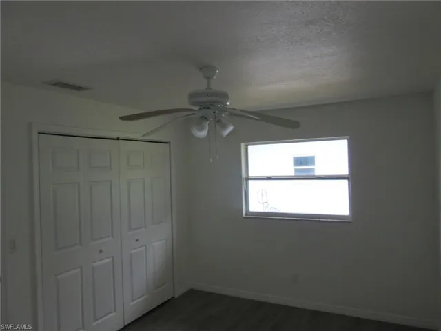 Unfurnished bedroom with a closet, ceiling fan, dark wood-style flooring, and a textured ceiling