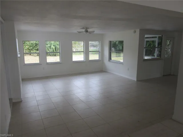 Spare room featuring healthy amount of natural light, ceiling fan, and light tile patterned floors