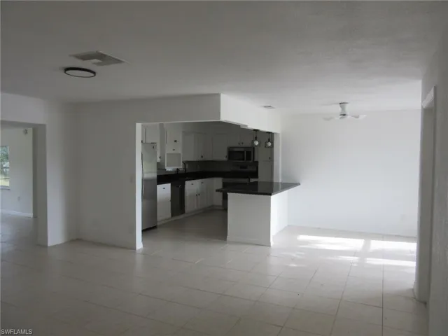 Kitchen featuring dark countertops, black appliances, open floor plan, and ceiling fan
