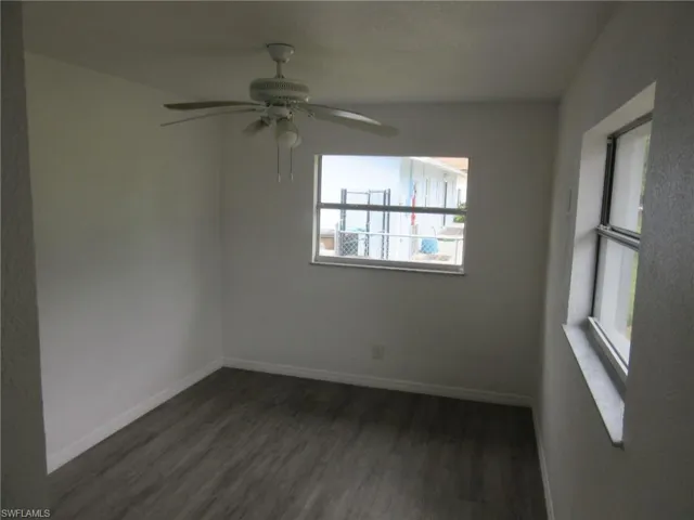 Unfurnished room with dark wood-style flooring and a ceiling fan