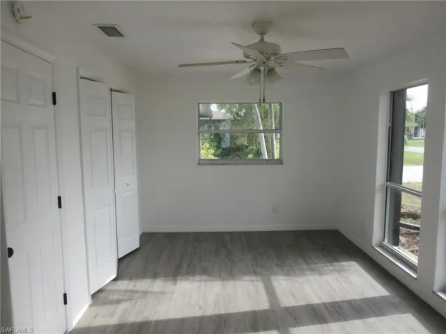 Unfurnished bedroom with light wood finished floors, a ceiling fan, and multiple closets