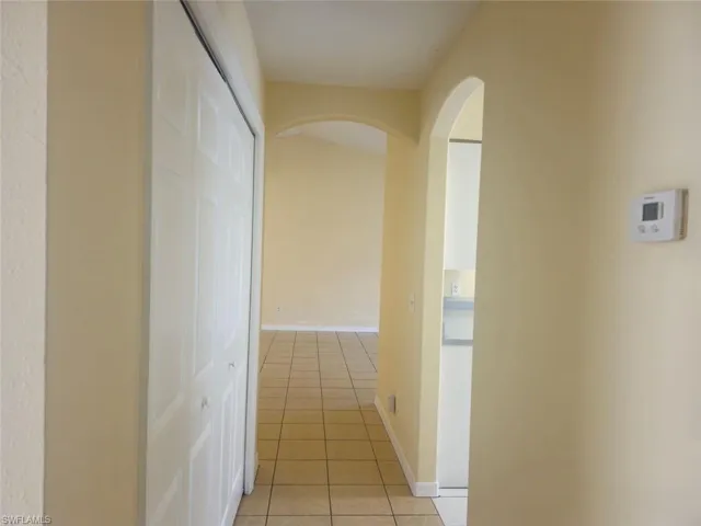 Hallway featuring light tile patterned floors and arched walkways