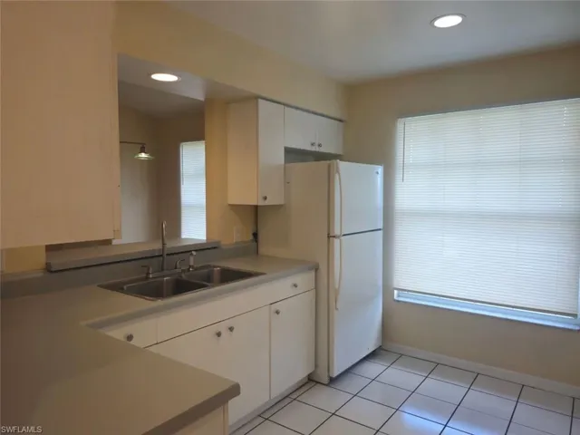 Kitchen with light countertops, light tile patterned floors, white cabinets, freestanding refrigerator, and recessed lighting