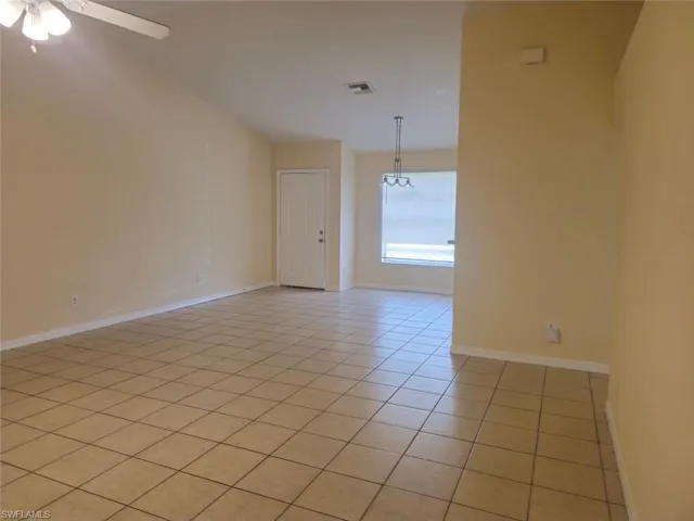 Unfurnished room with light tile patterned flooring and a chandelier