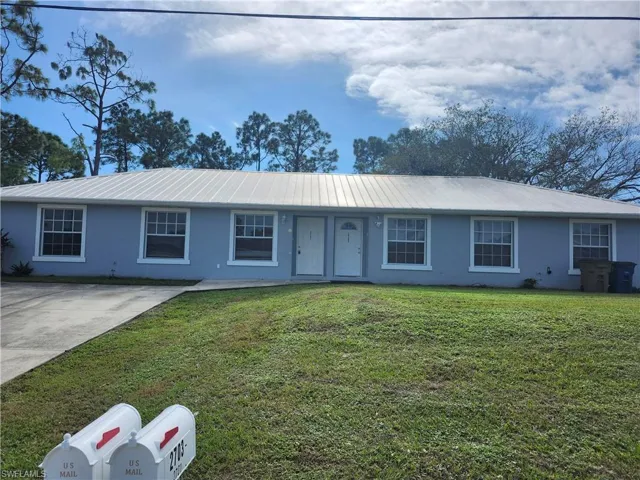 Ranch-style house with a front yard, a metal roof, and stucco siding
