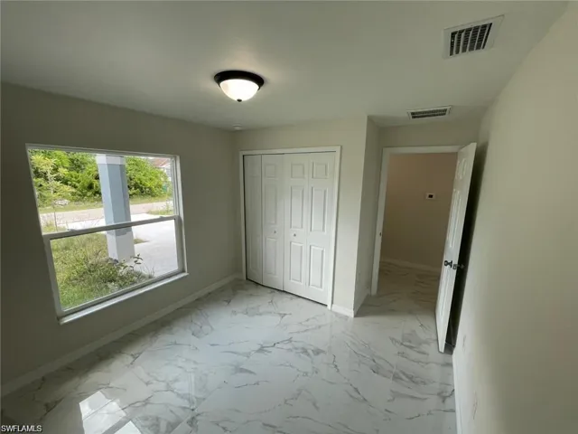 Unfurnished bedroom with light marble finish flooring and a closet