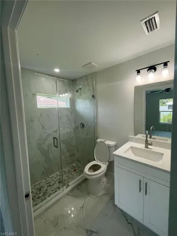 Full bathroom featuring a marble finish shower, vanity, and marble finish flooring