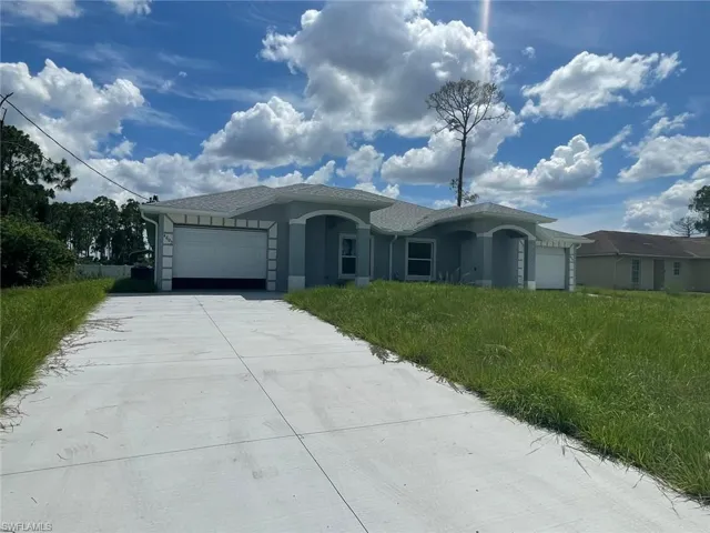 Single story home featuring a garage, concrete driveway, and stucco siding