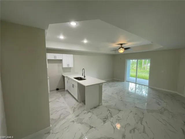 Kitchen with a raised ceiling, a ceiling fan, recessed lighting, open floor plan, and white cabinets