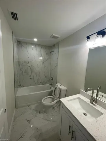 Full bathroom with marble finish flooring, vanity, and bathtub / shower combination
