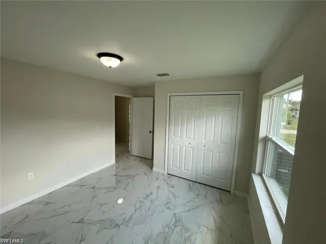 Unfurnished bedroom with light marble finish floors and a closet