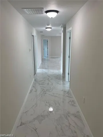 Hallway featuring baseboards and light marble finish flooring
