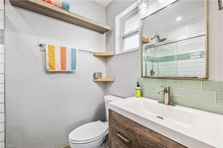 Bathroom with decorative backsplash, toilet, and vanity