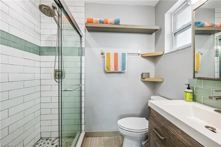 Bathroom with a shower with door, toilet, and vanity