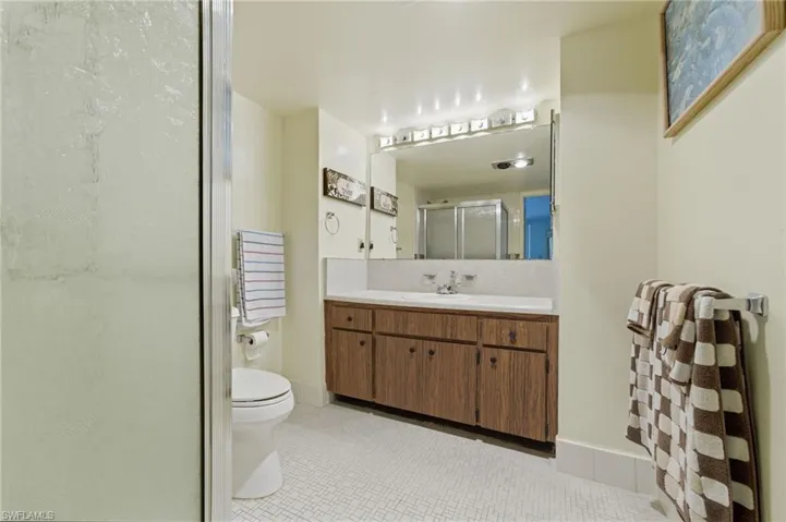 Bathroom featuring vanity, a shower stall, light tile patterned floors, and backsplash