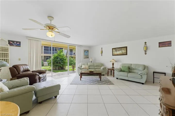 Living area with expansive windows, tile patterned floors, and a ceiling fan