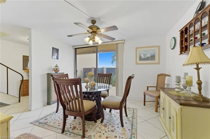 Dining space featuring light tile patterned floors, a ceiling fan, expansive windows, and stairs