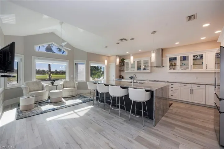 Kitchen featuring glass insert cabinets, dark stone counters, white cabinetry, pendant lighting, and a breakfast bar