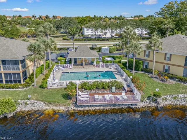 Aerial perspective of suburban area with a nearby body of water and a pool area