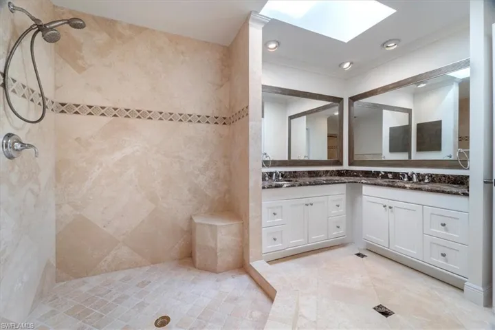Bathroom with crown molding, tiled shower, vanity, and a skylight