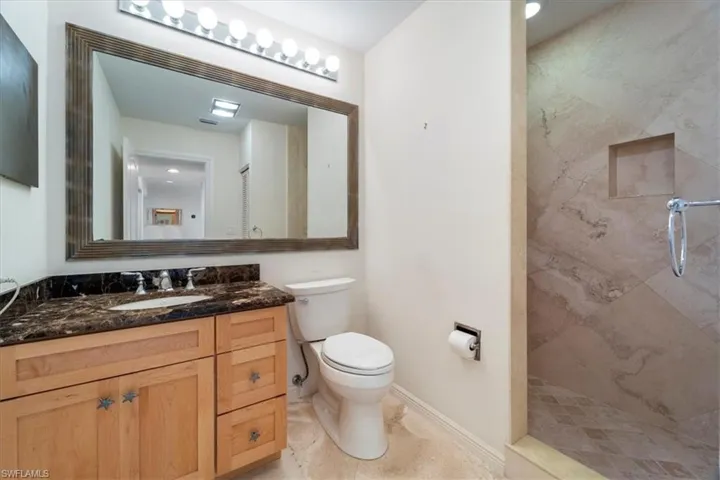 Bathroom with vanity, a tile shower, and toilet