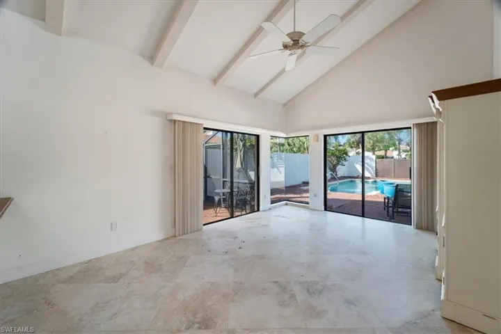 Spare room with ceiling fan, beam ceiling, and high vaulted ceiling