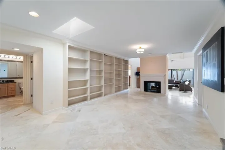 Unfurnished living room with crown molding and a skylight
