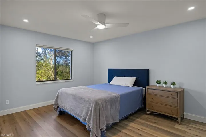 Primary bedroom with high hats and laminate wood-style flooring