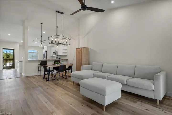 Open concept great room with laminate wood like  flooring, vaulted ceiling, and ceiling fan