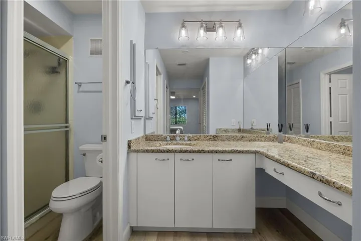Primary bathroom featuring granite counters, contemporary lighting and laminate flooring