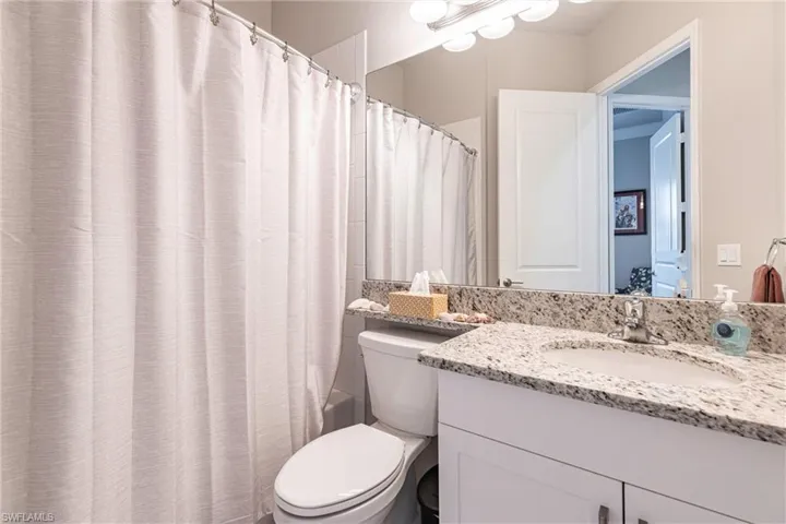 Bathroom featuring toilet, vanity, and shower / bath combination with curtain