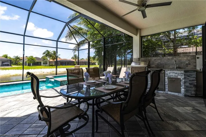 View of patio / terrace with a ceiling fan, a lanai, outdoor dining area, a pool with connected hot tub, and a sink