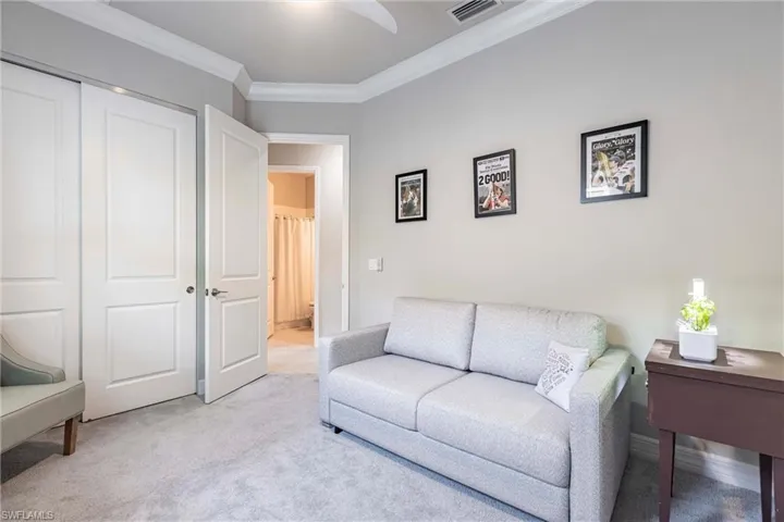Living room with ornamental molding and light colored carpet