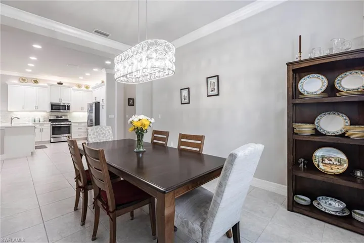 Dining space featuring ornamental molding, light tile patterned floors, a chandelier, baseboards, and recessed lighting