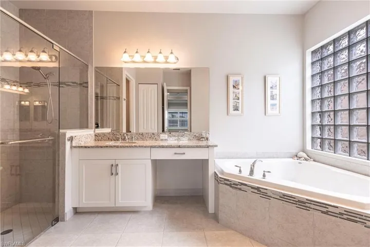 Full bathroom featuring a garden tub, double vanity, a stall shower, and tile patterned floors