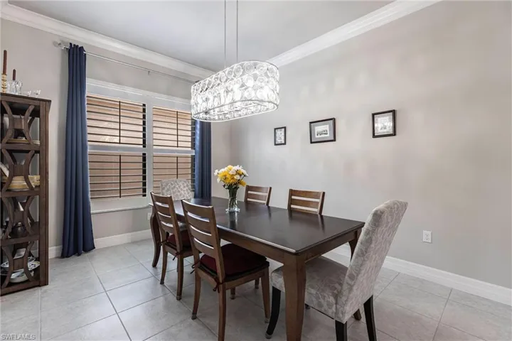Dining area featuring light tile patterned flooring, crown molding, baseboards, and a chandelier