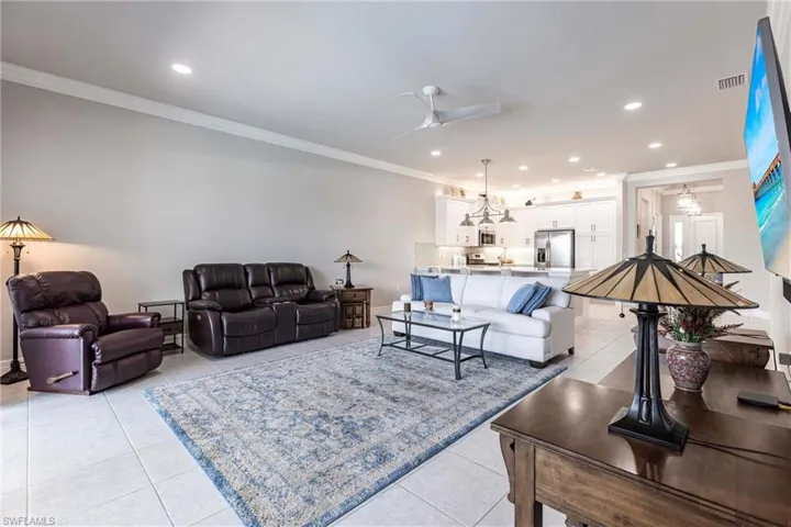 Living area featuring light tile patterned floors, crown molding, recessed lighting, a ceiling fan, and baseboards