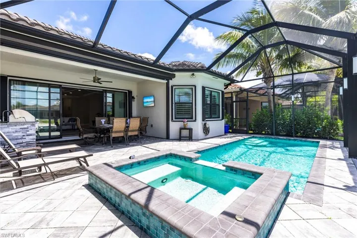 View of swimming pool with a patio area, outdoor dining space, a ceiling fan, and a pool with connected hot tub