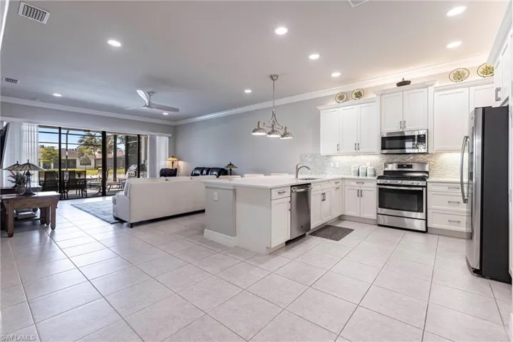Kitchen featuring stainless steel appliances, open floor plan, crown molding, backsplash, and light tile patterned flooring