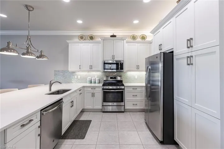 Kitchen featuring stainless steel appliances, a sink, crown molding, tasteful backsplash, and a peninsula
