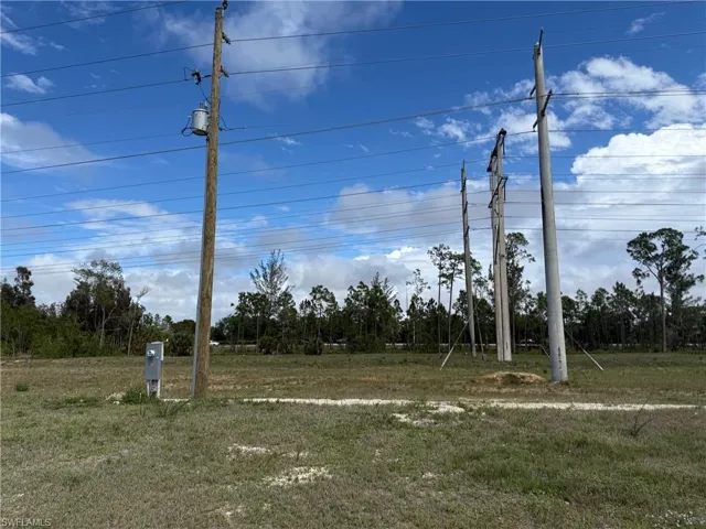Expansive raw land parcel featuring a utility pole with an attached transformer, overhead power lines, and a dedicated utility box