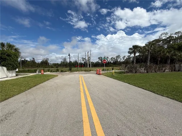 Paved roadway with double yellow lines, bordered by green grass and natural landscaping